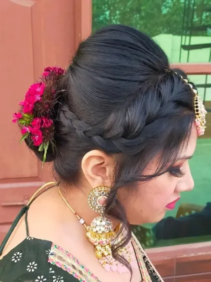 Hairstyling is key to completing the look. Here is an example of an intricate braided bun, adorned with fresh flowers, perfect for a bride or wedding guest wanting an elegant and secure hairstyle.
