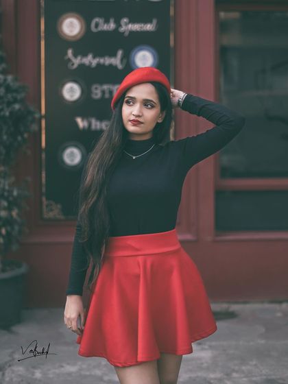 Using a cafe storefront as a backdrop to enhance the European city feel. The moody color grading in this shot adds a vintage, cinematic quality to the 'girl from Paris' concept.