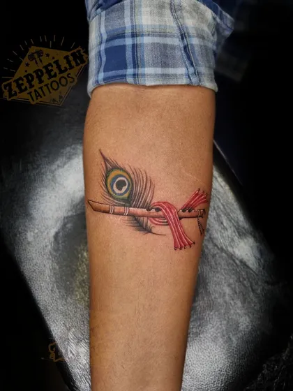 The final Krishna's flute tattoo, with rich color in the peacock feather and red cloth, completely camouflaging the scar underneath.