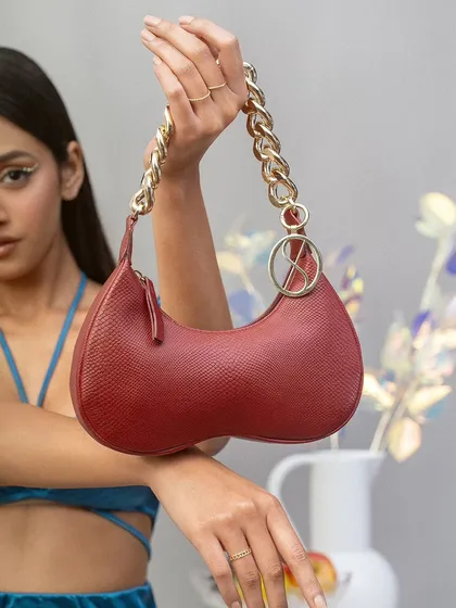 A detailed product-in-use shot for the Sarjaa handbag campaign. The focus is on the bag's texture, hardware, and how it is held, providing key visual information for a potential customer.