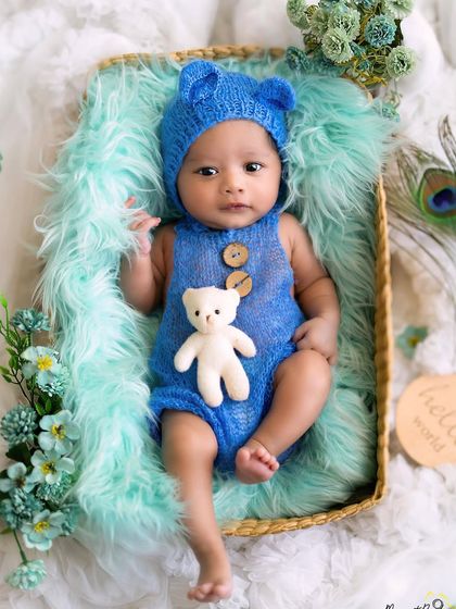 A little bear cub saying hello to the world. This newborn boy in his adorable blue knit outfit looks so sweet and alert in his cozy basket.