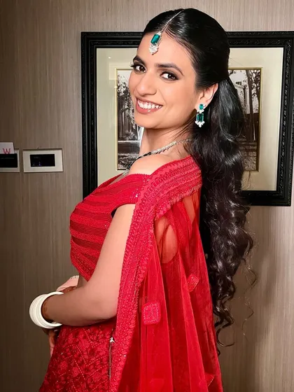 A whole lot of love and a whole lot of red. Soft glam at its finest for this client's post wedding celebrations, featuring a modern red lehenga and a chic, wavy ponytail.