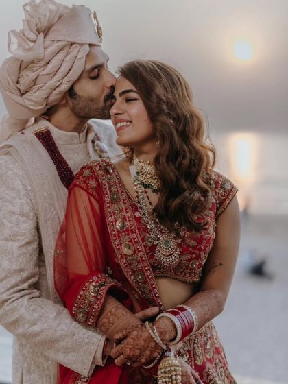 A tender moment between the bride and groom. Her mehendi-adorned hands add a touch of tradition and beauty to this romantic, sun-kissed photograph.