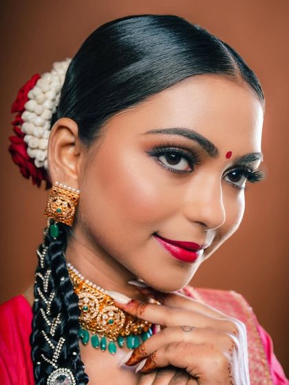 A smiling portrait of the South Indian bride, showcasing the complete look with the traditional braided hairstyle and flowers.