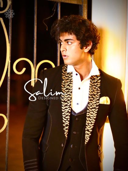 A young model in a black three-piece suit with a gold patterned waistcoat and lapel. This look is perfect for a festive occasion or wedding event.