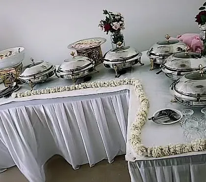 A compact setup for a housewarming party for 25 guests. The use of floral arrangements and elegant white linens makes the space feel special.