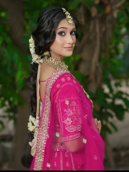 A side profile showcasing the hairstyle and jewellery with our rani pink lehenga. The gold jhumkas and maang tikka are part of our rental jewellery collection.