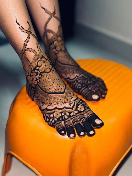 A beautiful bridal foot design with intricate patterns and a leafy vine extending up the leg.
