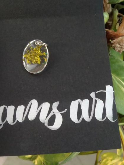 An oval-shaped pendant with a small yellow flower inside. This shows the variety of shapes and floral inclusions I offer for my custom pendants.