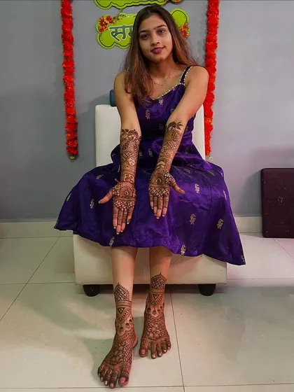 A full-length shot of the bride, showing her complete mehendi on both hands and feet. She looks absolutely radiant.