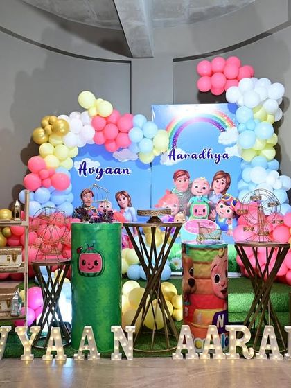 Here is another fun Cocomelon theme, complete with character cutouts, a rainbow backdrop, and light-up marquee letters spelling out the children's names. It's a bright and cheerful setup for young fans.