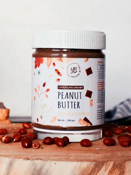 A clean, bright product shot of YB Peanut Butter, surrounded by peanuts on a wooden board to highlight its primary ingredient.