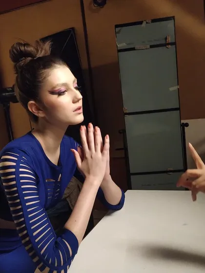 A behind-the-scenes shot from a beauty editorial. This shows the model in position, with my graphic purple eyeliner look ready for the photographer's direction.
