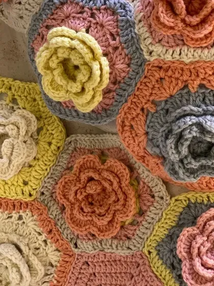 A close-up of hand-crocheted hexagonal flowers from the 'Hope You're Well' installation. These tactile details, made with soft yarns, were central to creating a space focused on wellbeing and empathy.