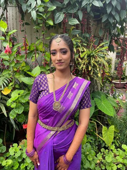 A full-length shot of the bride in her purple saree, looking elegant and poised.