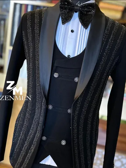 A three-piece black tuxedo with vertical stripes of shimmering beadwork. The double-breasted waistcoat adds a classic touch to this modern, sparkling design.