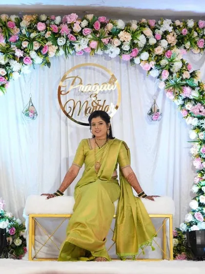 The bride posing on the stage we created for her engagement. The white sofa and floral arch with a custom name hoop make for a perfect solo portrait spot.
