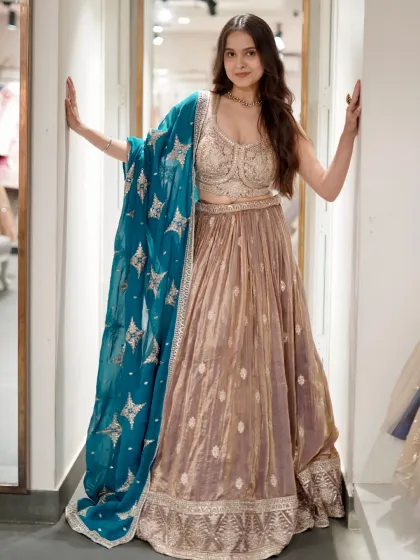 A beautiful beige lehenga paired with a contrasting teal dupatta. The star motifs on the dupatta add a touch of magic to this elegant outfit.