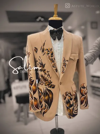 A beige blazer on a mannequin, brought to life with bold, hand-painted abstract floral designs. This is a perfect piece for a daytime event or a destination wedding.