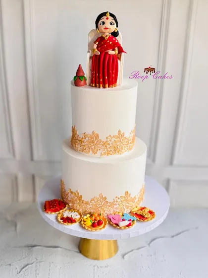 A traditional welcome for a new baby. This Dohale Jevan (Maharashtrian baby shower) cake features a beautiful hand-modelled figure in a classic red saree, surrounded by intricate gold stenciling and traditional offerings.