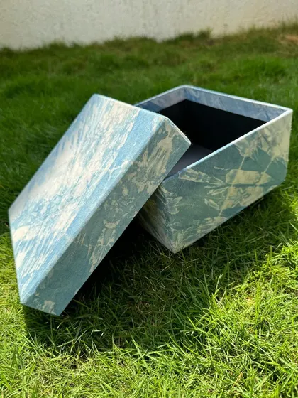 The indigo box, open on the grass. It's perfect for storing jewelry, stationery, or other small treasures, adding a touch of handmade elegance to your space.