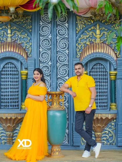 A bold and colorful shot with the couple posing against an ornate blue and gold backdrop, coordinating with a bright yellow gown.