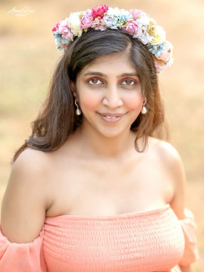 A lovely close-up portrait focusing on the mother's happy and serene expression. The floral crown adds a touch of bohemian charm to her look.