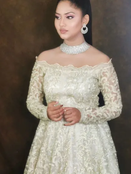 Your reception or cocktail party look is sorted with this elegant off-shoulder gown. The intricate ivory and gold lacework gives it a designer feel, and it pairs beautifully with a simple American diamond choker.