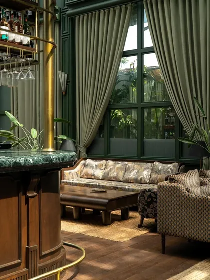 A view from the bar, looking out into the lounge. The green marble of the bar top complements the deep green of the architectural structure.