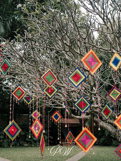A close-up of the colorful hangings and bells used to decorate a tree for an outdoor Mehendi ceremony, adding a touch of whimsy.