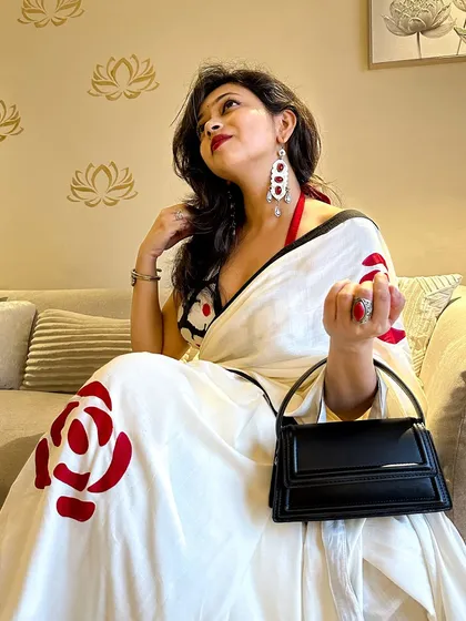 Accessorizing the saree look with beautiful red and silver earrings that pick up the colors from the saree's rose motifs. Accessories are what truly complete an outfit.
