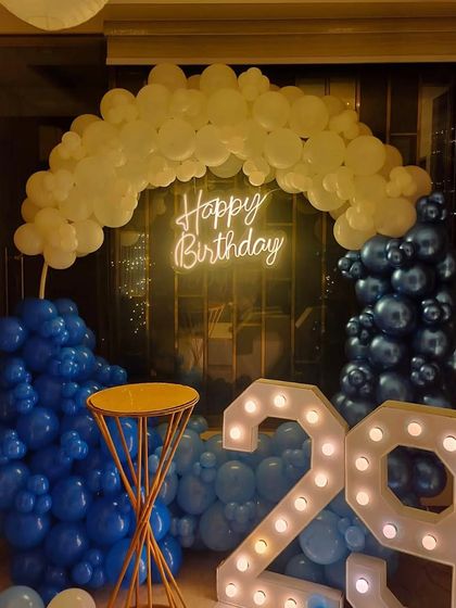 A close-up of a 29th birthday decoration, showing the blue and white balloon arrangement, neon sign, and light-up numbers.