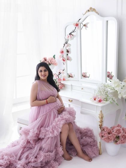 A portrait of a queen on her throne. Seated gracefully by the vanity, this mom-to-be radiates confidence and joy in her magnificent ruffled gown.