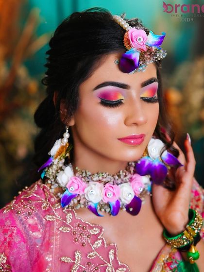 A close-up on the colorful eye makeup and floral jewelry, demonstrating skills in creating looks for pre-wedding ceremonies.