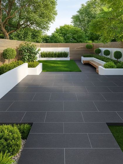 A minimalist backyard design featuring a pristine lawn bordered by raised white planters with neatly pruned shrubs. The dark grey tiled patio provides a sharp, modern contrast to the greenery.