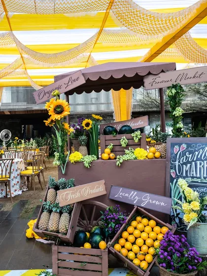 A creative "Farmer's Market" stall at the Haldi, filled with fresh fruits and sunflowers, adding a rustic and interactive element to the decor.