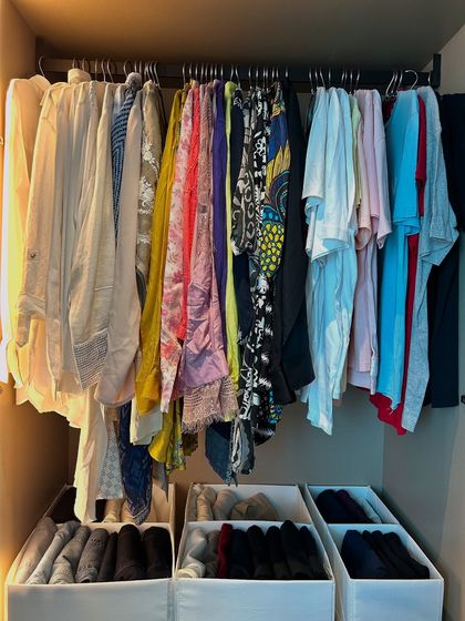 This closet uses bins on the shelves to contain folded items, preventing stacks from becoming messy.
