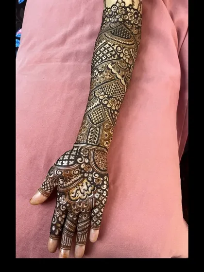 A side view of a full arm bridal mehendi, showcasing the seamless flow of geometric and traditional patterns from the hand to the elbow.
