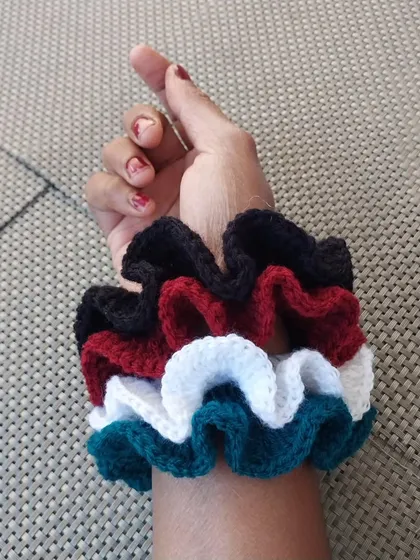 A stack of my colorful crochet scrunchies worn on the wrist. They are as stylish as a bracelet as they are in your hair.