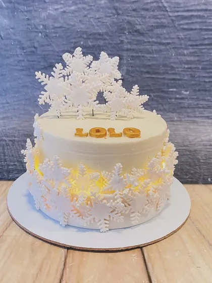 A stunning winter-themed cake that lights up from within. The design is adorned with intricate white snowflakes, creating a magical glowing effect.
