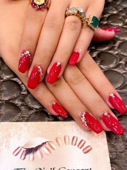 A glamorous set of bright red coffin nails. The design is elevated with delicate clusters of crystals placed at the base of each nail.