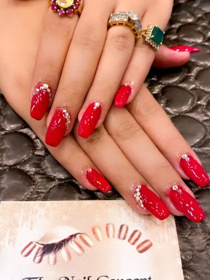 A glamorous set of bright red coffin nails, perfect for making a statement. Each nail is adorned with a delicate cluster of crystals at the base for a touch of sparkle.