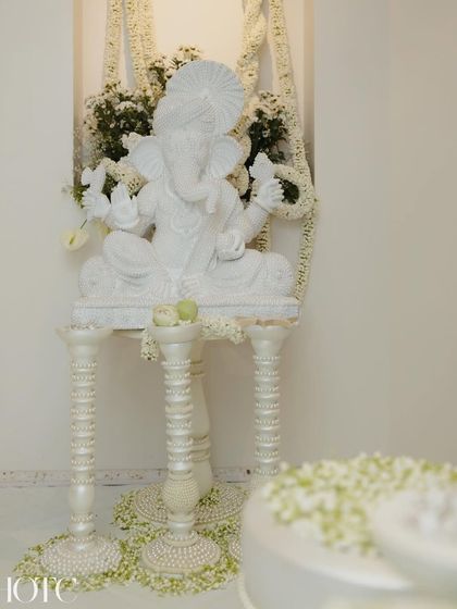 A beautiful white Ganesha statue adorned with pearls and fresh flowers, a serene and auspicious element in the 'Ghar ki shaadi'.