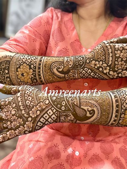 A beautiful shot of the back of the hands, covered in intricate peacock and floral designs.