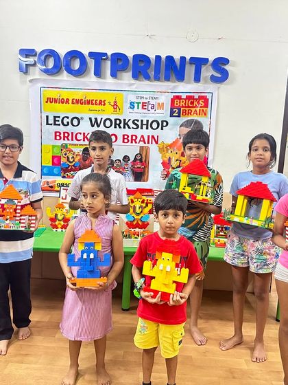 A group of young builders at our Footprints center location pose with their completed LEGO Ganpati idols and pandals. Each child holds their unique creation, demonstrating the success of our guided building session.
