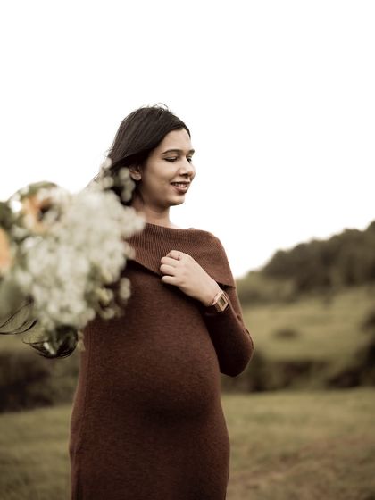 A beautiful portrait of the mom-to-be with the wind in her hair, holding a bouquet. Her happy, relaxed expression captures a moment of pure contentment.