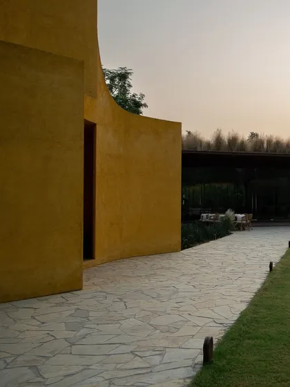 A pathway leads towards the pavilion at dusk, a transition from the open lawn to an intimate dining space.