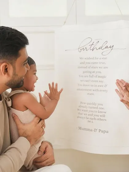 Celebrating a first birthday with claps and smiles. This candid moment captures the family's joy as they read a beautiful birthday message, marking a very special milestone.