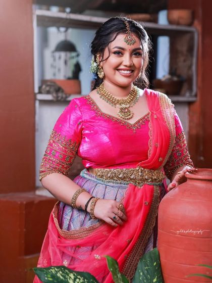 A cheerful and vibrant outdoor shoot featuring a model in a pink and purple half-saree. The playful poses on a swing and the bright colors capture a youthful and joyous spirit.