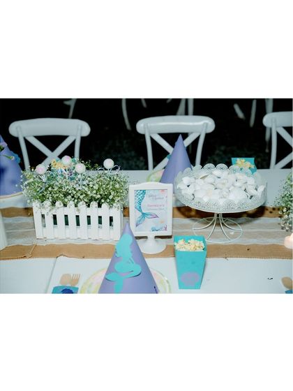 A close-up of the place setting at our mermaid party, featuring themed hats, popcorn boxes, and a small sign.